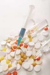 syringe on the background of tablets and pills.