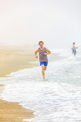 cute young teenage boy joging at the empty beach in the morning