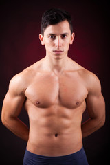 Fototapeta na wymiar Portrait of a young muscular man against black background