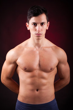 Portrait of a young muscular man against black background