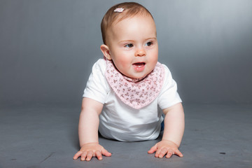 Fototapeta premium Cute baby girl against grey background. Studio shot.