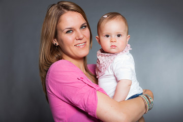 Happy young mother in love with her baby daughter. Studio shot.