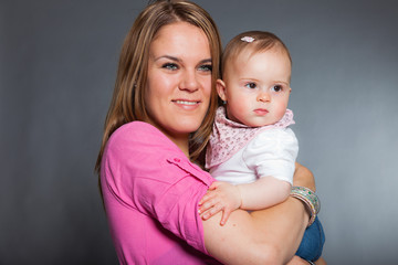 Happy young mother in love with her baby daughter. Studio shot.