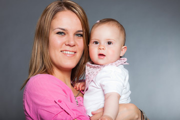 Happy young mother in love with her baby daughter. Studio shot.