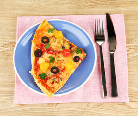 plate with a slice of delicious pizza on wooden background