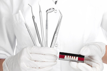 Naklejka premium Set of dental tools and denture in dentists hands