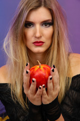Halloween witch with red apple on color background