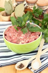 Bowl of raw ground meat with spices on wooden table