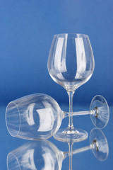 Two empty wine glasses on color background