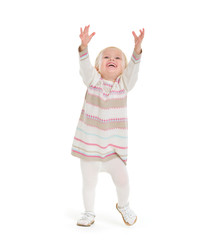 Baby girl in knit winter clothing pulling up to get something