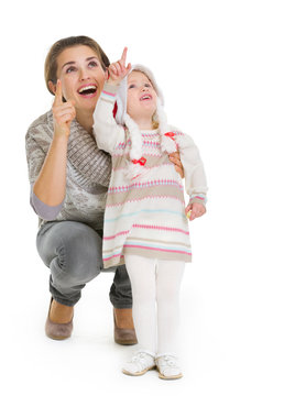 Christmas Portrait Of Happy Mother And Baby Girl Pointing Up