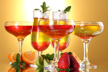fruit jelly in glasses and fruits on yellow background
