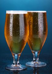 Glasses of beer on blue background