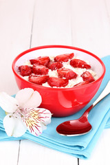 Cottage cheese in red bowl with sliced strawberries