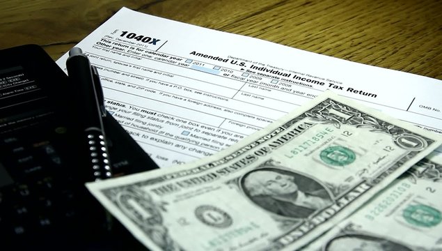 Tax return concept. 1040X and hand counting money.