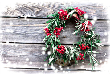 Christmas  wreath with red berry on a rustic wooden wall