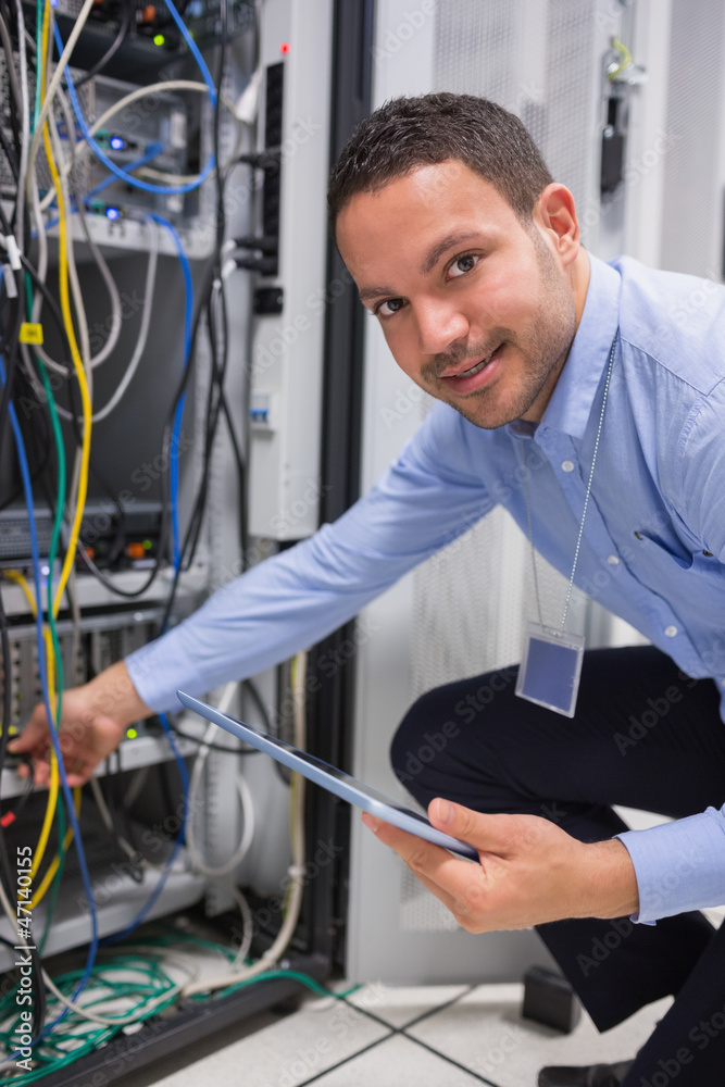 Poster technician plugging in cables and using tablet pc