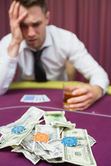 Man with whiskey glass leaning on poker table in casino