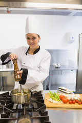 Happy chef adding pepper to soup