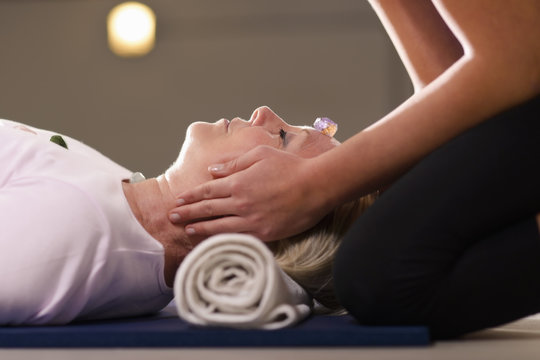 Young Therapist Arranging Crystals On Female Client For Reiki Th