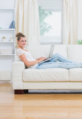 Obraz premium Woman using laptop lying on the couch