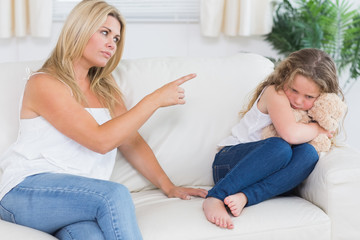 Mother scolding daughter clutching teddy bear