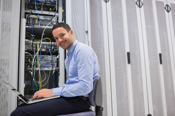 Naklejka na ściany i meble Uśmiechnięty mężczyzna pracuje na serwerach