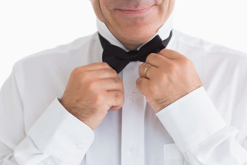 Smiling man fixing bow tie