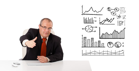 Businessman sitting at desk with diagrams and graphs