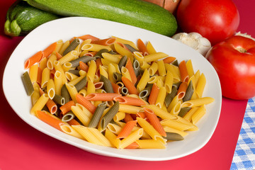Bowl of uncooked tri-color pasta and ingredients
