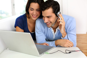 Cheerful young couple chating on internet with webcamera