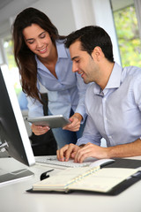 Office workers in front of desktop computer with tablet