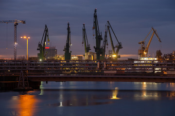 Obraz premium Big cranes and bridge at the shipyard at night.