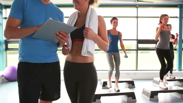 Women doing aerobics while trainer talking with woman