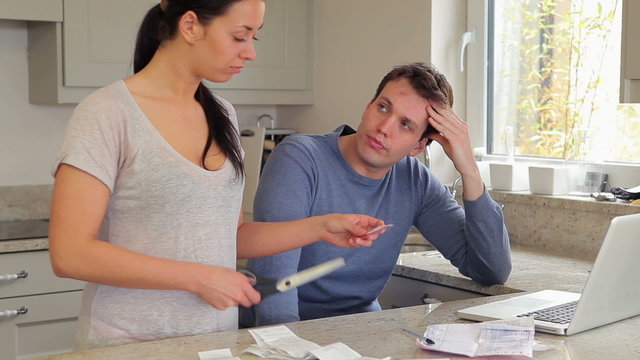 Couple stressing over finances with woman cutting credit card