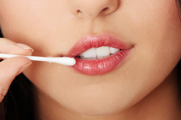 Woman touching her lips with cotton stick