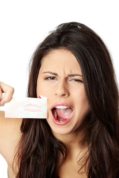 Young woman taking of tape from her mouth.
