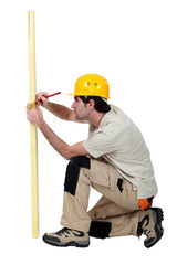 Tradesman marking a measurement on a wooden plank