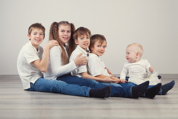 Group of kids in jeans sitting on floor