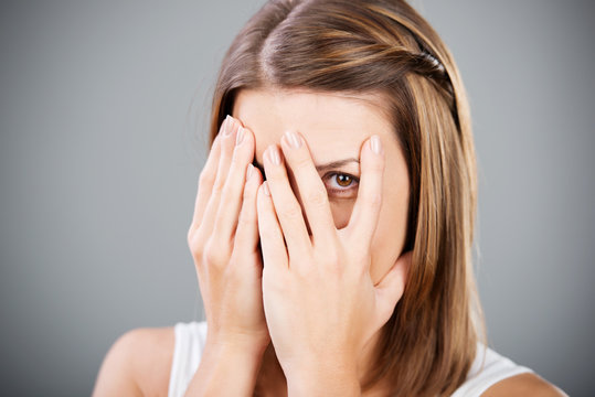 frau versteckt sich hinter h&auml;nden