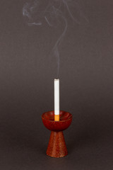 Burning cigarette in a candleholder