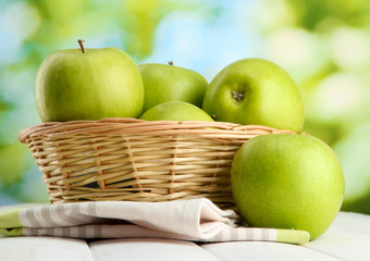 Ripe green apples with leaves in basket,