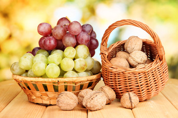 Grape in basket with nuts on wooden table