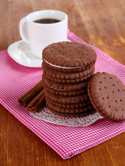 Chocolate cookies with creamy layer and cup of coffe