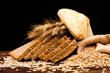 assortment of baked bread on wooden table and black background