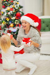 Obraz na płótnie Canvas Mom and baby girl changing Christmas presents