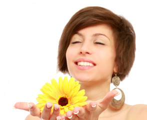 A smiling woman is holding a yellow gerbera