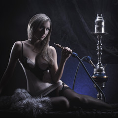 A young blond woman in lingerie smoking a hookah