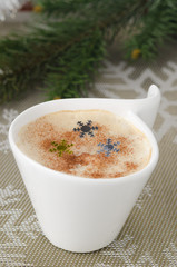 Cup of cappuccino on the table, fir branches in the background