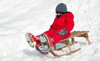 Kid sliding with sledge in the snow.